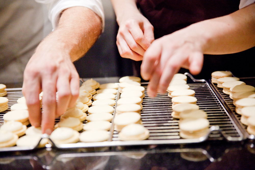 Macarons werden von Hand mit Creme gefüllt